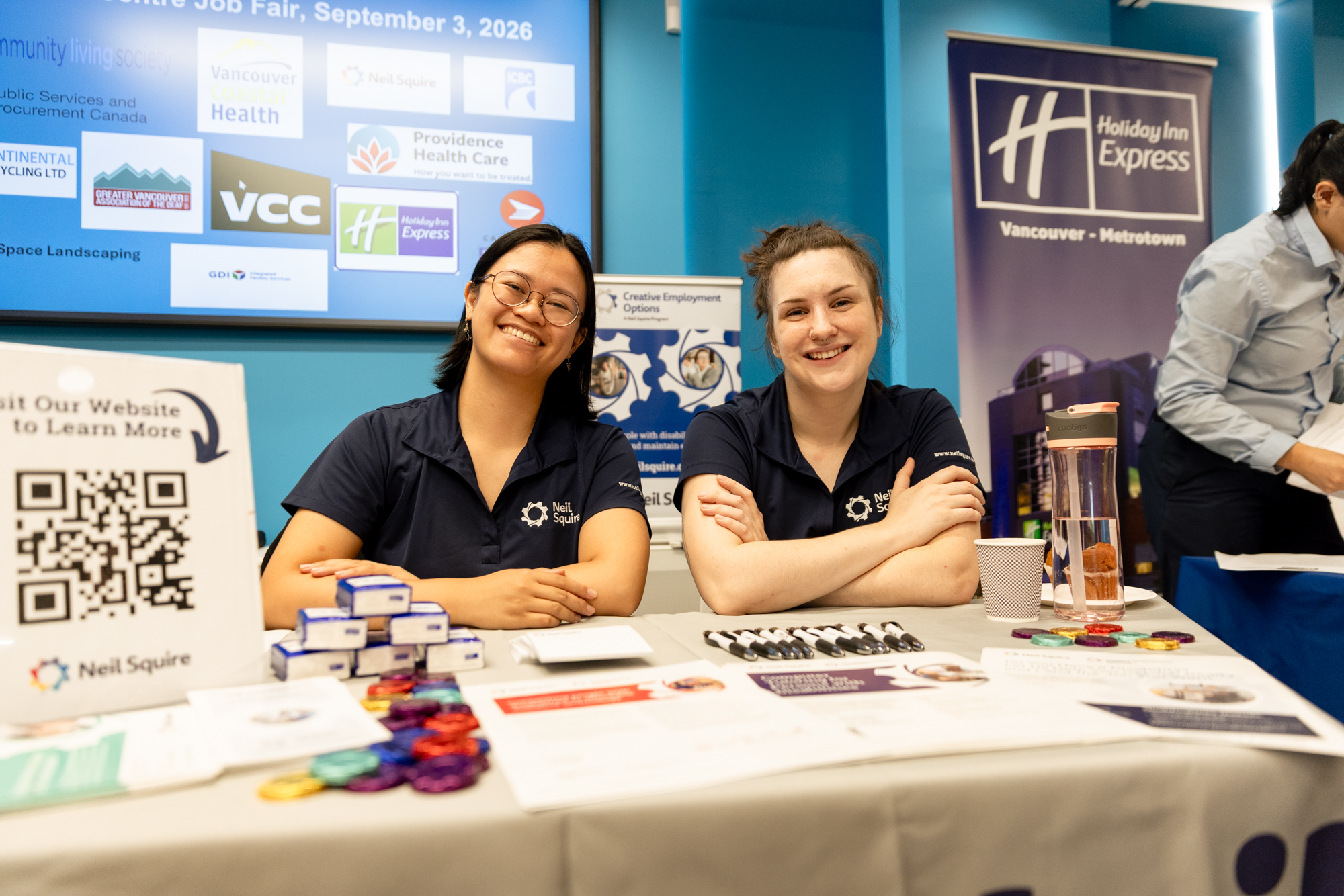 Two Neil Squire representatives smile behind an information table at Wavefront Centre’s 2026 Job Fair.