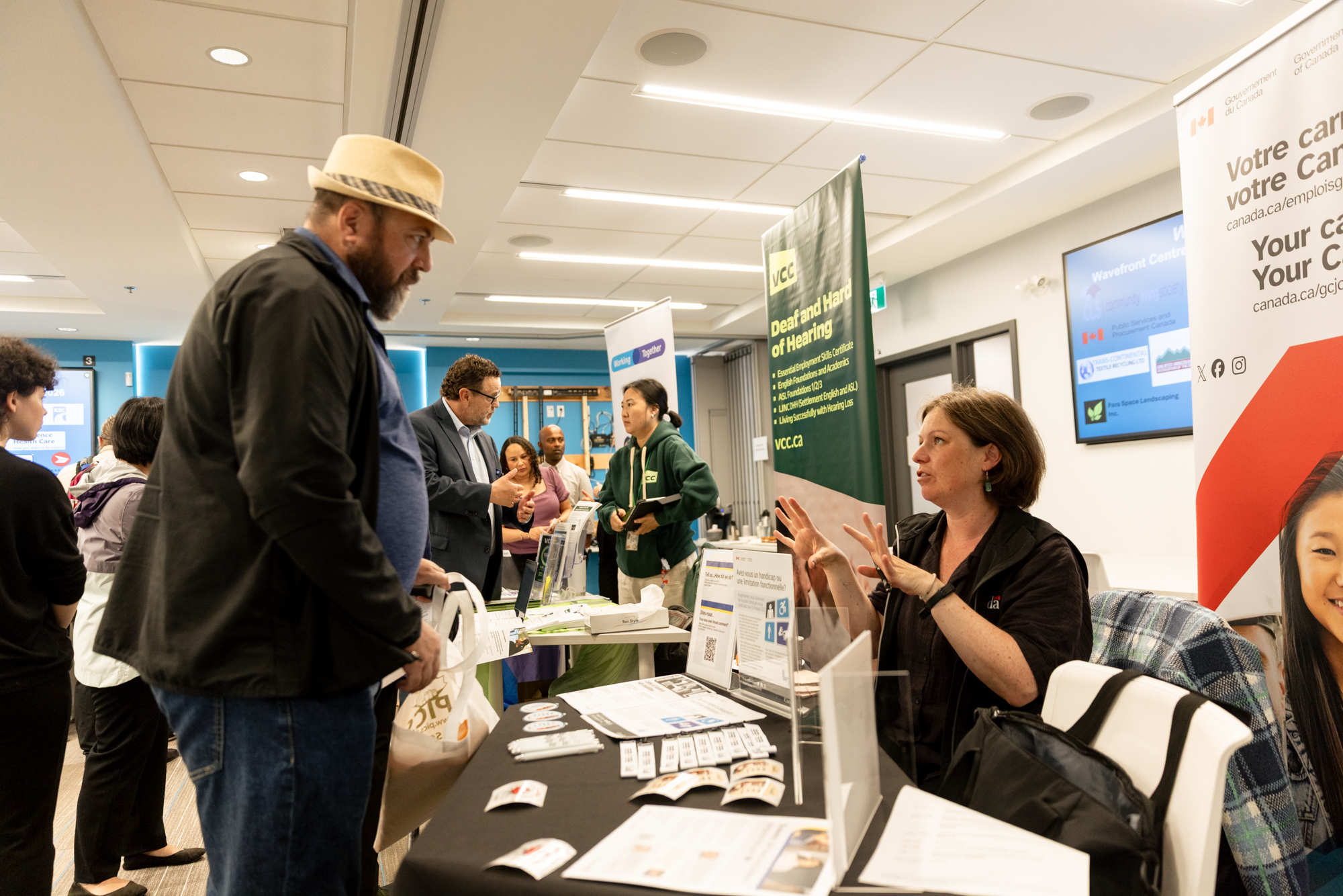 A job seeker speaks with a Government of Canada representative at an information table during Wavefront Centre’s 2026 Job Fair.