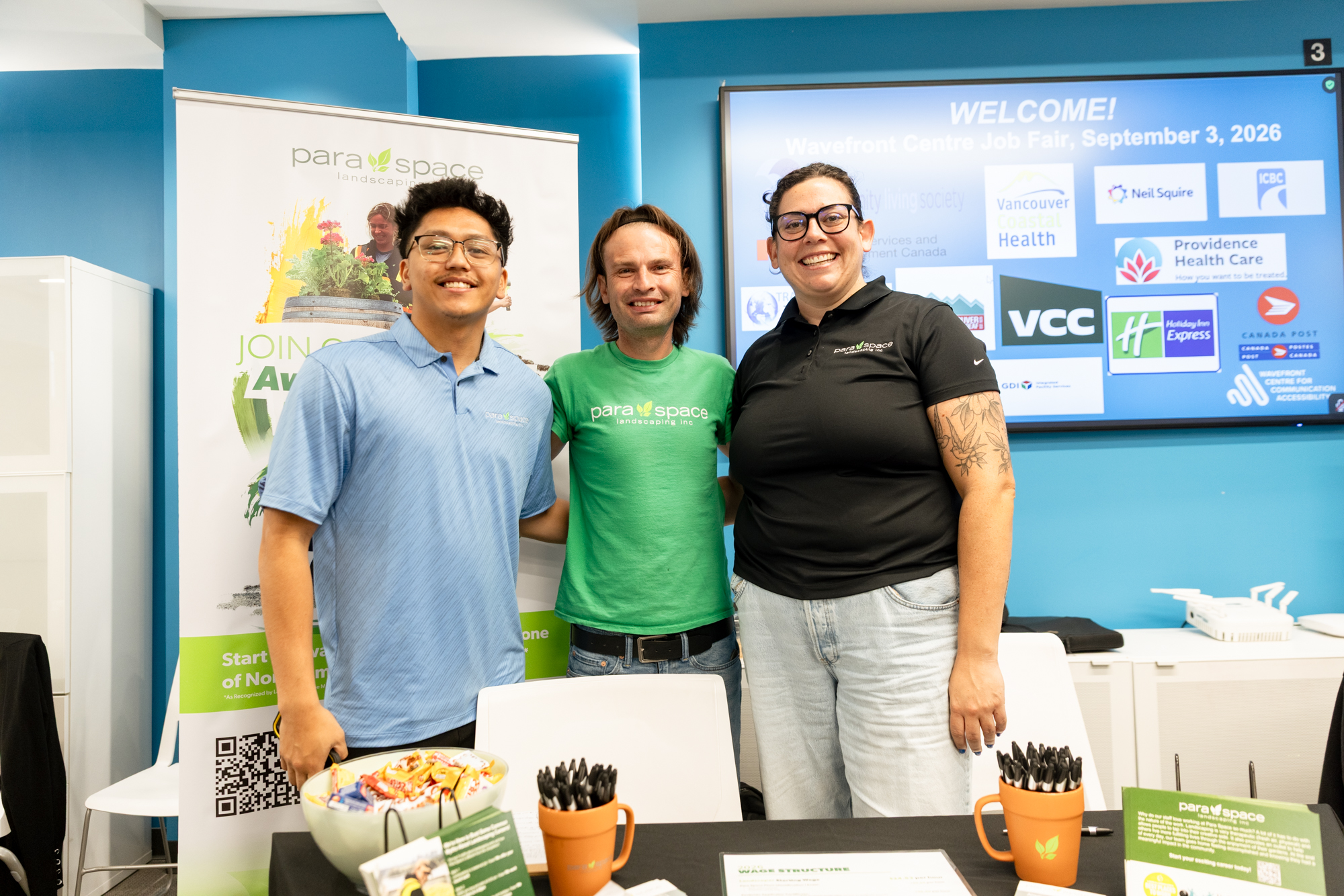 Three Para Space Landscaping representatives smile behind their information table at Wavefront Centre’s 2026 Job Fair.