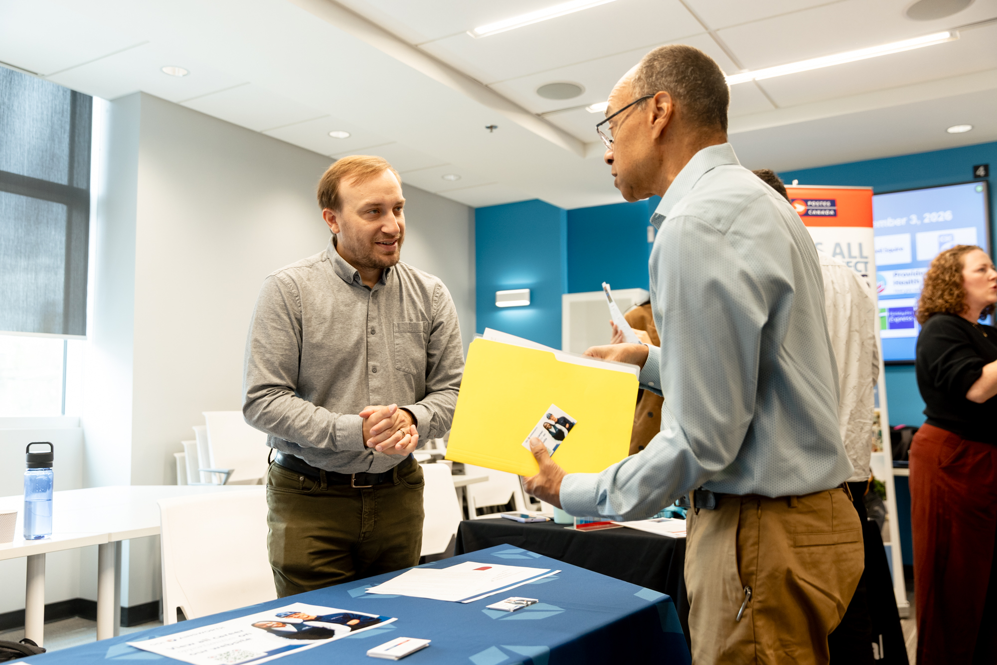 Two men converse at an employer booth during Wavefront Centre’s Employment Services Job Fair.